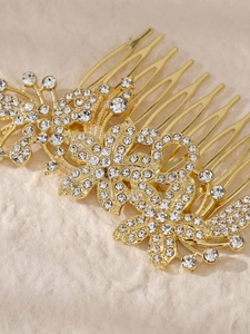Nahaufnahme eines goldenen Brauthaarkamms mit funkelnden Kristallblumen und Blattmuster