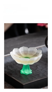 Close-up of elegant lotus shaped frosted glass tea cup with vibrant green tall stem