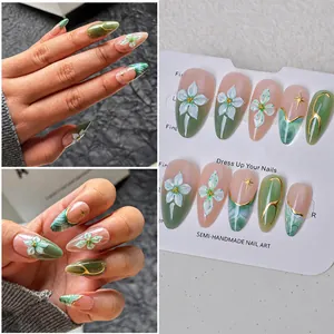 Detail of emerald green almond nails with 3D white flowers and gold star patterns