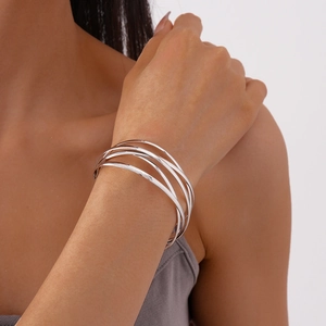 Close-up of a silver multi-layer geometric cuff bracelet worn by a model in a minimalist style