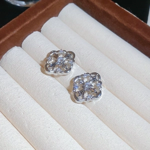 Macro shot of silver cross earrings with zircon crystals and hollow gothic engraving