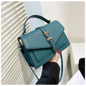Close-up of deep teal PU leather bag with gold buckle detail and sturdy top handle