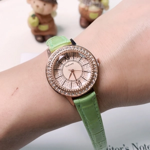 Close-up of a women's watch with rose gold rhinestone bezel and green leather strap