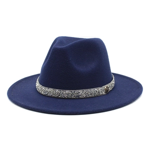 Detail of navy blue wool fedora hat featuring a sparkling rhinestone band and metal M logo