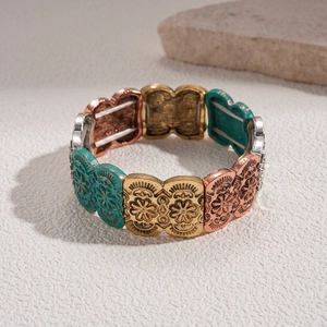 Detail of vintage carved metal bangles with bohemian patterns on a textured stone base