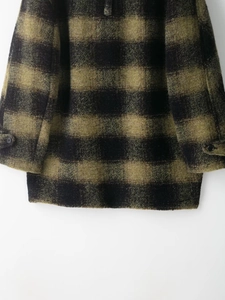 Detail of wool blend plaid coat showing fabric texture on hem and cuff area