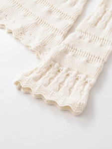 Close-up of white hollow-out knit sleeve featuring intricate floral patterns and scalloped edges