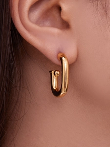 Gros plan détaillé d'une boucle d'oreille créole en forme de U plaquée or 18 carats sur l'oreille