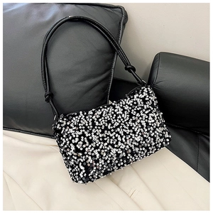 Detail shot of sparkling silver sequins and knotted leather handle on black shoulder bag