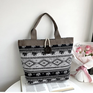 Close-up of ethnic print canvas tote bag with woven handles and elephant pattern details