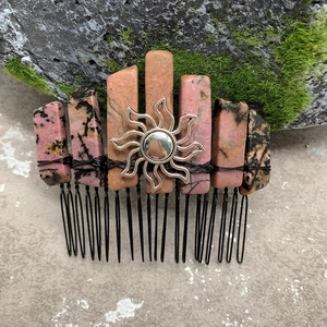 Detailed close-up of handmade crystal hair comb with sun emblem and black wire wrap