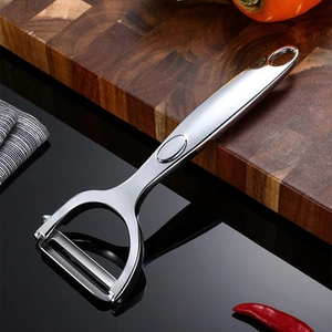 Detail of stainless steel vegetable peeler with ergonomic handle on wooden board