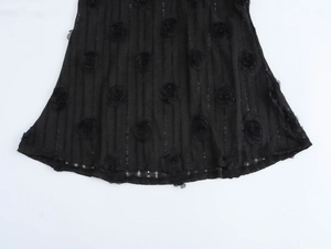 Détail de la rose 3D noire et texture côtelée verticale sur une robe longue moulante