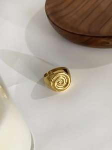 Macro detail of vintage gold spiral conch pattern on stainless steel hollow ring