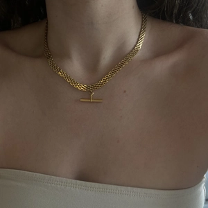 Detail of a gold-plated T-bar pendant on a flat woven snake chain necklace for women