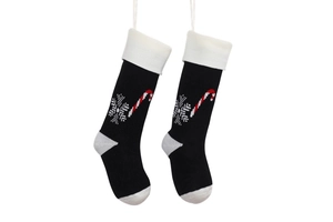 Detail of a black knitted Christmas stocking with white snowflake and candy cane patterns