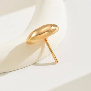 Close-up of minimalist golden oval hair hook with a smooth metallic finish on textured white