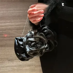 Detail of a black satin rose-shaped evening clutch bag with a detachable silver chain strap