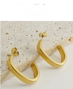 Macro shot of 18k gold plated C-shape earrings with textured horizontal stripe details