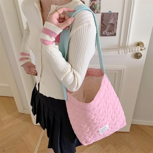 Detailed close-up of pink quilted tote bag with blue shoulder strap and interior pocket