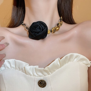 Dettaglio choker a rosa in seta nera con catena in metallo dorato e trama floreale