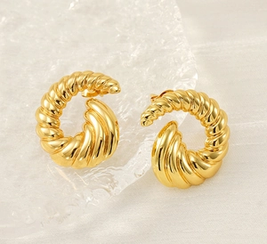 Macro shot of 18k gold plated spiral twist earrings on a textured background
