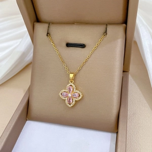 Detail of pink crystal clover necklace in a luxury velvet gift box on white silk fabric