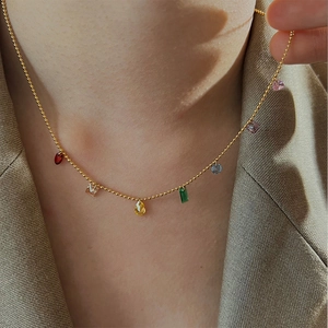 Close-up of a gold beaded necklace with multi-colored teardrop and geometric gemstones
