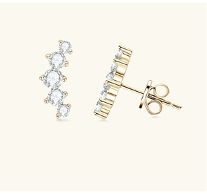 Detail view of gold stud earrings with five sparkling stones in a curved arrangement