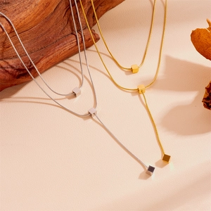 Détail macro de colliers à pompons minimalistes en acier inoxydable doré et argenté