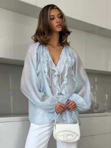 Detail of sheer light blue blouse with ruffles and lantern sleeves with ties