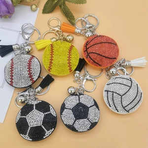 Flat lay of rhinestone sports ball keychains with matching leather tassels and bells