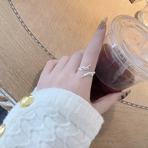 Silver twig-shaped multi-layer ring worn by a model holding a coffee cup on wood