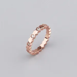 Detail view of rose gold scalloped ring band with micro-set zircon stones on gray background