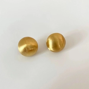Macro shot of three-piece golden spherical earrings with a brushed matte metallic texture