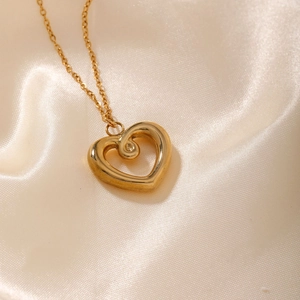 Detail of a hollow gold heart pendant necklace with spiral texture on champagne silk
