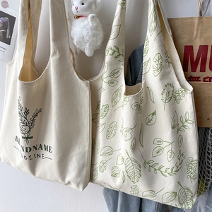Detail of two beige canvas tote bags with green plant prints and soft natural lighting