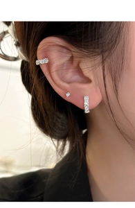 Detail of silver U-shaped earring set with zircon stars and cuffs on a female model