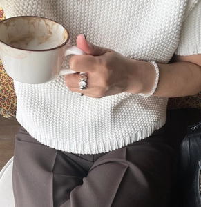 Close-up of irregular silver 925 ring and woven bracelet worn with a casual outfit