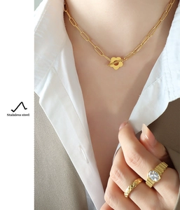 Detailed close-up of a gold flower pendant necklace and gemstone ring set on a model