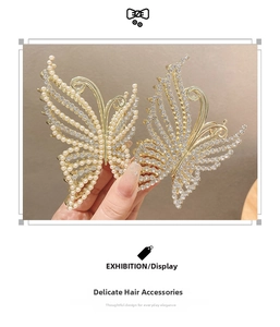Close-up of golden butterfly hair clips with pearls and rhinestones on hollow wings