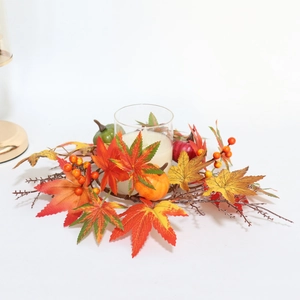 Close-up of harvest wreath with maple leaves, pumpkin, and glass candle holder