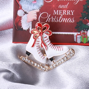 Détail d'une broche patin à glace blanc avec nœud rouge sur fond de soie argentée