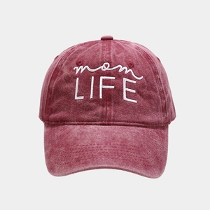 Close-up of washed cotton texture and white 'mom LIFE' embroidery on vintage red baseball cap