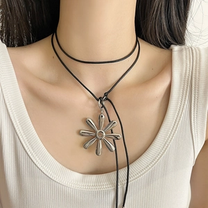 Close-up of a large silver flower pendant on a minimalist black cord necklace