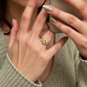 Detail of a gold maple leaf ring with white zircons worn on a model's finger