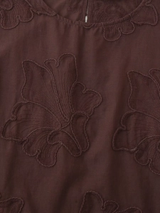 Vue macro détaillée de broderies florales sur le tissu d'un gilet marron chocolat