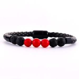 Detail of woven leather bracelet with black lava stone, red beads, and magnetic clasp