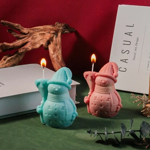 Blue and pink snowman candles with knit texture details in a festive holiday scene