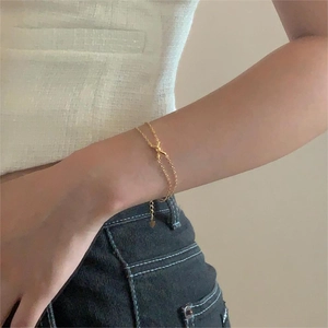 Close-up of golden double-layer twisted chain bracelet with knot detail and heart pendant